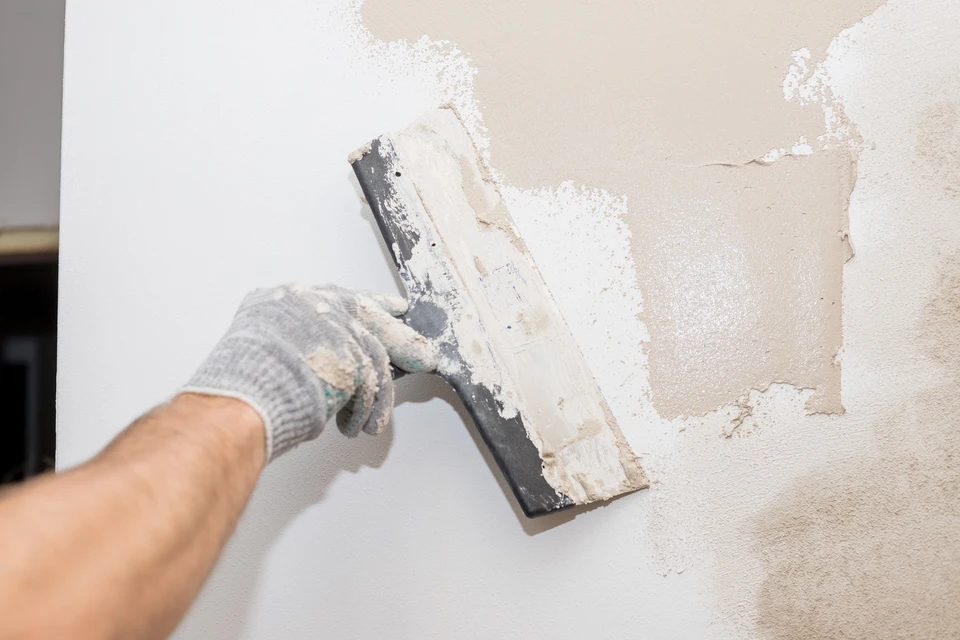 Intérieur de chantier avec ouvrier appliquant enduit sur mur