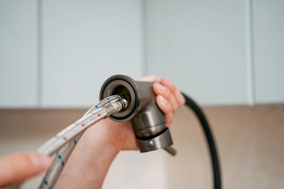 Intérieur de cuisine moderne, homme installant un tiroir en bois massif avec poignée métallique dans un meuble blanc