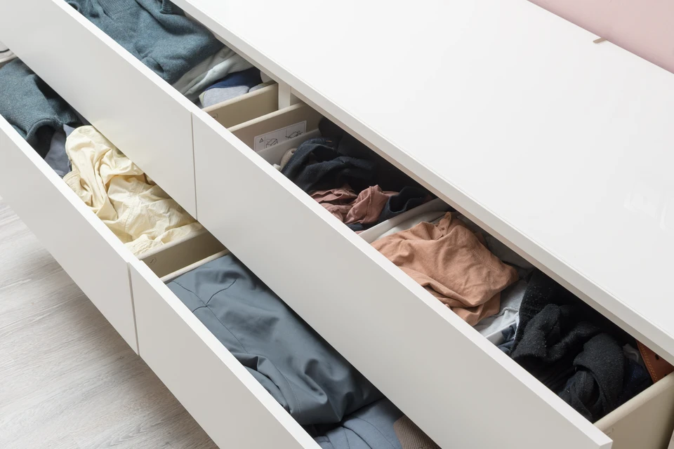 Vue d'un dressing sur mesure aménagé dans une chambre ou un espace résidentiel, montrant des modules de rangement en bois naturel ou finition moderne s'étendant du sol au plafond, avec penderies, étagères, et tiroirs organisés de manière fonctionnelle. L'espace est bien éclairé et rangé, démontrant une utilisation optimale du volume disponible et une harmonie visuelle d'ensemble.