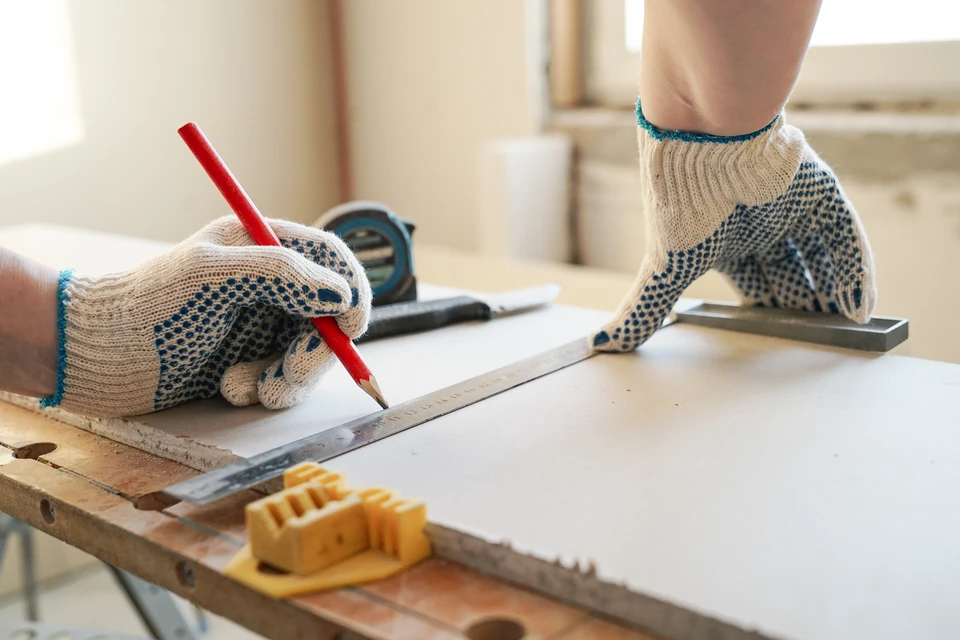 Homme d'affaires en costume sombre et chemise claire exprimant la joie et le succès, poings levés en signe de victoire dans un couloir de bureau moderne avec baies vitrées et plante verte